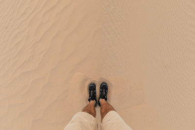 Low section of person standing on sand