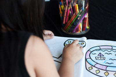 Girl drawing on book at table