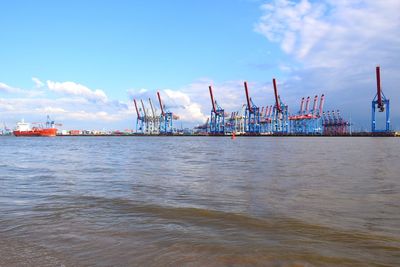 Cranes at commercial dock against sky