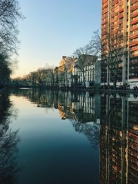 Reflection of buildings and trees in lake against sky