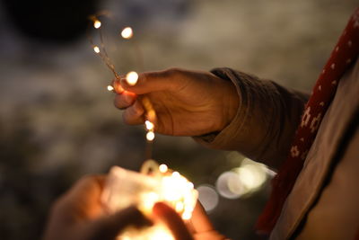 Close-up of hand holding burning candle