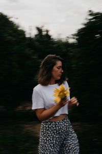 Young woman looking away while standing on tree