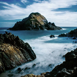 Scenic view of rocks in sea against sky