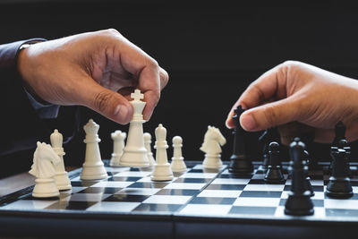 Close-up of people playing chess against black background