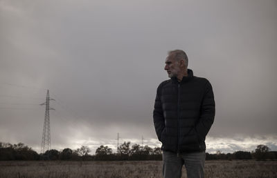 Adult man in winter clothes in fields against cloudy sky