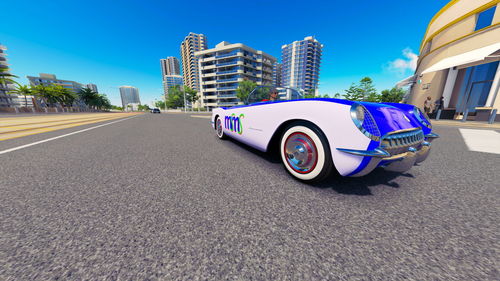 Vintage car on road by buildings against blue sky