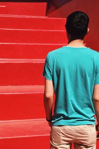 Rear view of man standing against red wall