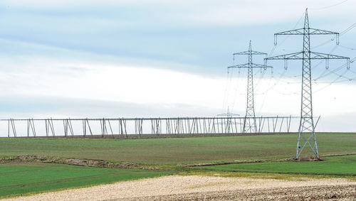 Electricity pylon on field against sky