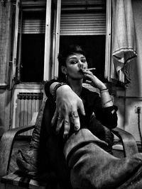 Woman holding cigarette while sitting at home