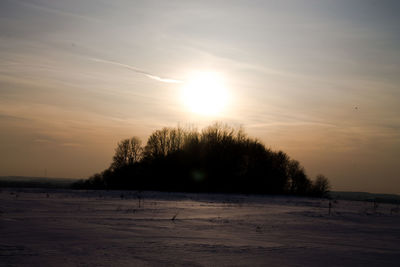 Scenic view of frozen landscape against sky during sunset