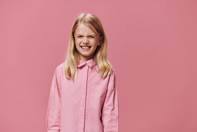 Portrait of young woman standing against yellow background