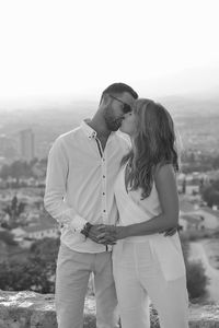 Romantic couple kissing against sky during sunset