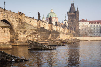 Low angle view of charles bridge and cathedral by river in city against clear sky