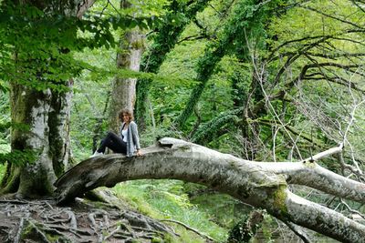 Man sitting on tree trunk against sky