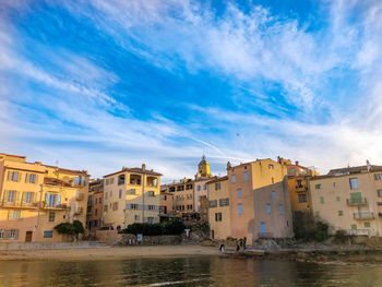 Buildings by river against blue sky