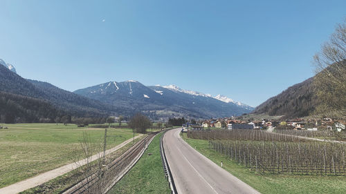 Empty road amidst field against clear sky