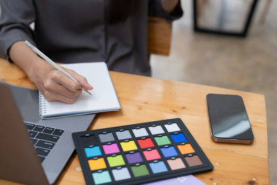 Midsection of woman using calculator while sitting on table