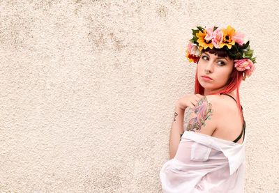 Portrait of young woman standing against wall