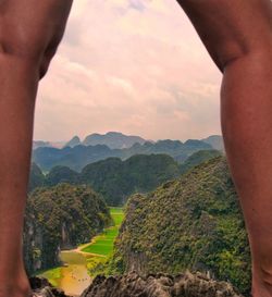 Cropped image of hand on mountain against sky