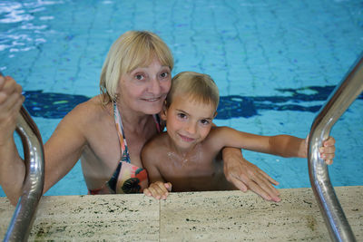 Woman in her 60s and grandson swim at public sports pool. family bond, active lifestyle, health