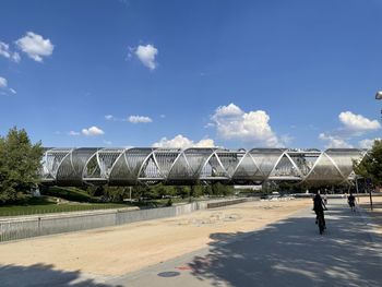 Man walking by built structure against blue sky