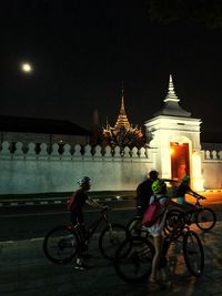 Bicycles against illuminated building in city at night