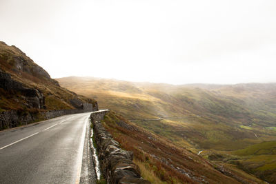 Road leading towards mountains against sky