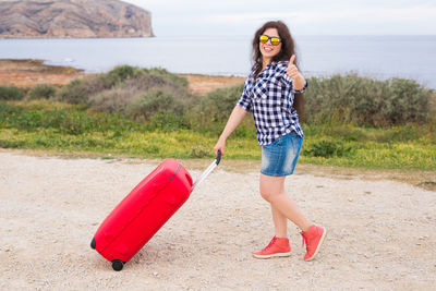 Full length portrait of young woman standing on land