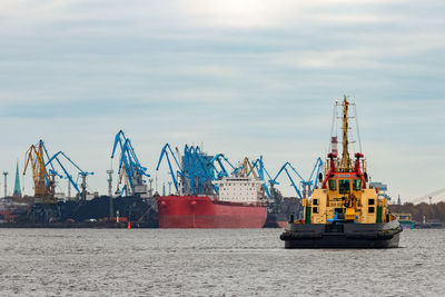 Cranes at commercial dock against sky