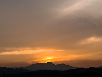 Scenic view of silhouette mountains against orange sky