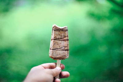 Hand holding ice cream cone against blurred background