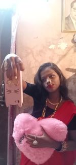 Portrait of woman holding pink while standing outdoors