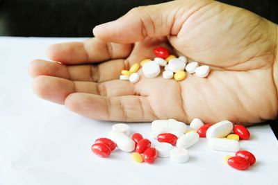 Cropped image of hand holding capsules on table