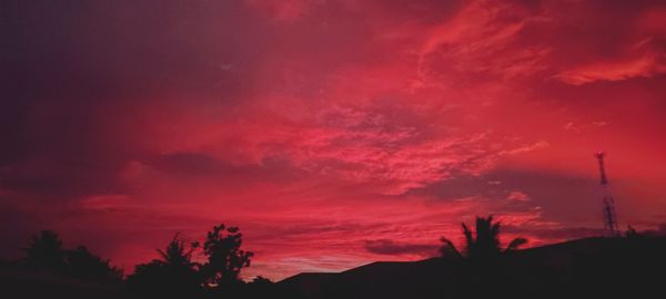Low angle view of silhouette trees against dramatic sky