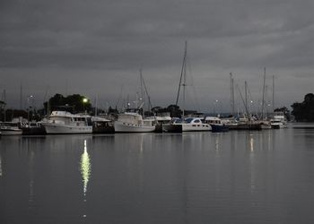 Sailboats moored in harbor against sky