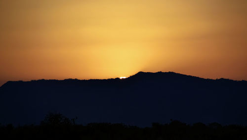 Scenic view of silhouette mountains against orange sky