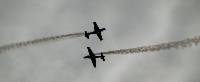 Low angle view of silhouette airshow in sky