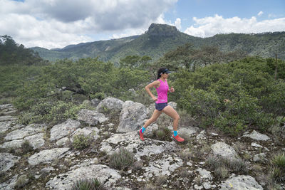 One girl with pink t shirt trail running on a high rocky surface