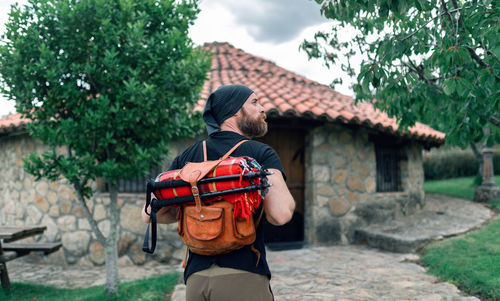 Man standing by house against plants