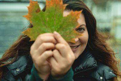 Portrait of woman holding leaf in park