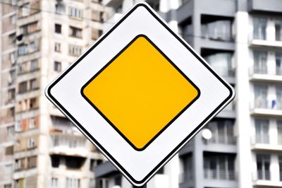 Close-up of yellow sign on metal in city