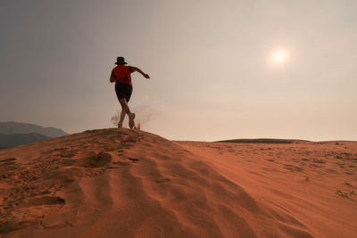 Rear view of man running on sand dune at desert