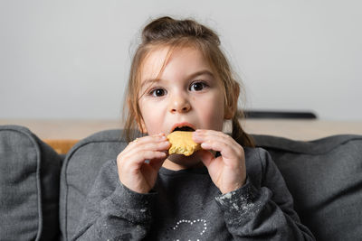 Portrait of cute girl eating biscuit at home