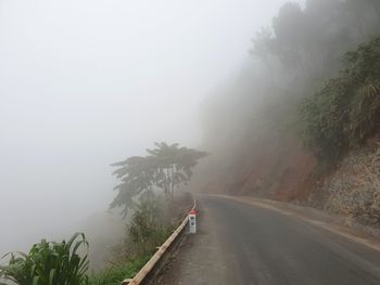 Road amidst trees against sky during rainy season