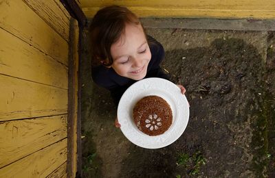 Directly above shot of smiling girl holding food in plate