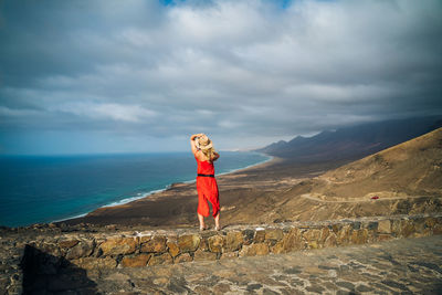 Woman standing on mountain by sea against sky