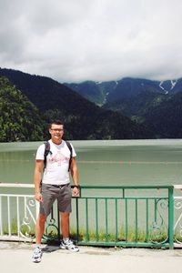 Portrait of young man standing on mountain against sky