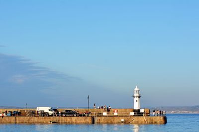 Lighthouse by sea against sky