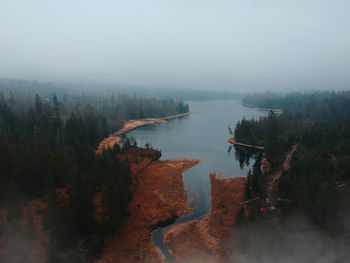 Scenic view of lake in forest against foggy sky