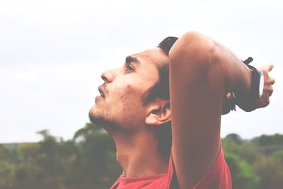 Close-up of young man looking away against sky